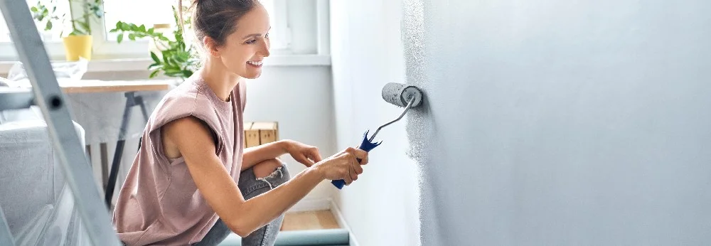 Person streicht Wand mit Farbrolle